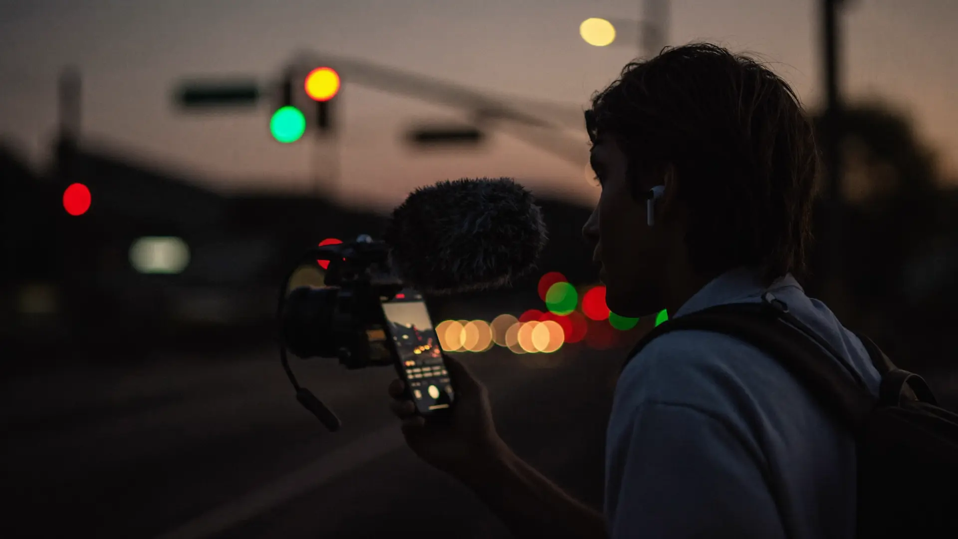 Field reporter recording on location at dusk with a phone rig